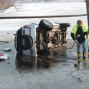 A tow-truck operator attempts to remove a Michigan KJ from a swamp after teenagers awkwardly parked it there
